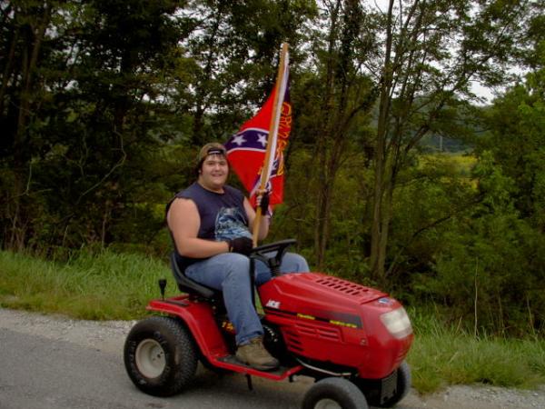 Some redneck driving down Hwy 37 on a lawn mower with a confederate flag that says, "Git'er done".