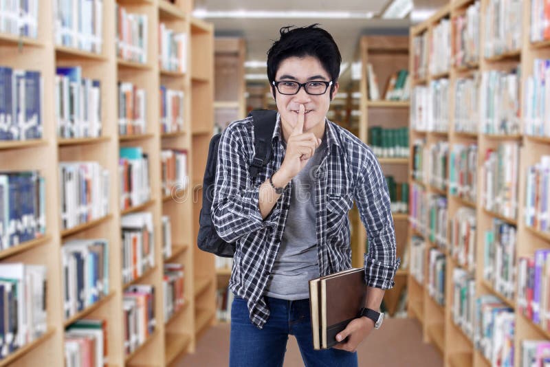 male-student-making-silence-sign-portrait-high-school-standing-library-make-54819074.jpg