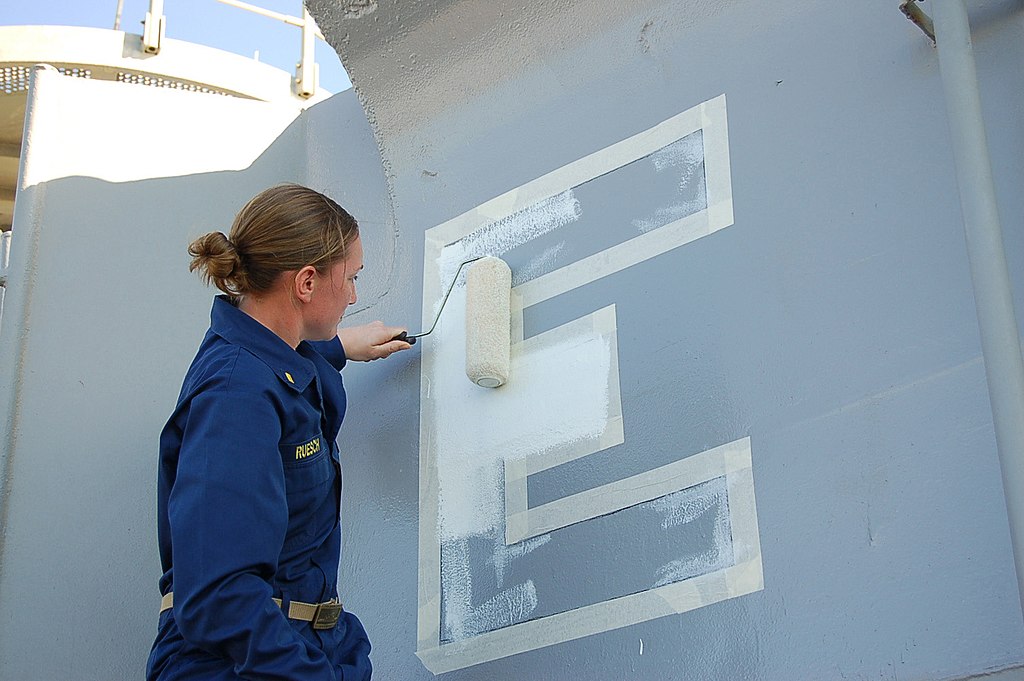 1024px-US_Navy_060314-N-8997S-003_Ensign_Rebecca_Ruesch_paints_the_Navy_Battle_E_on_the_amphibious_transport_dock_ship_USS_Austin_(LPD_4).jpg